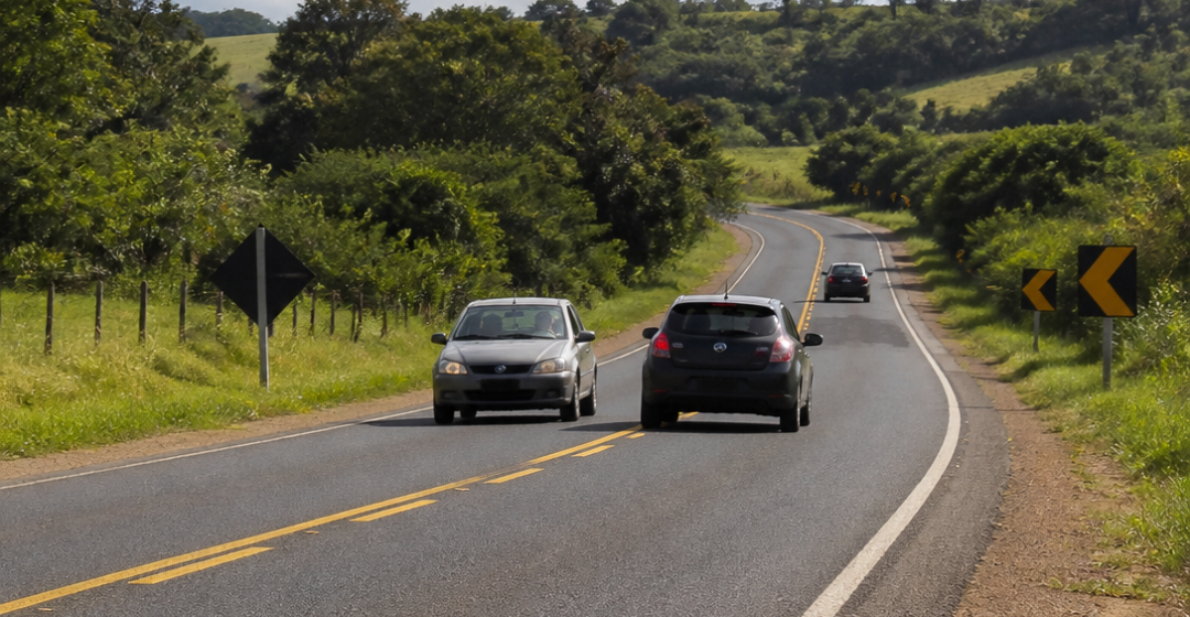Carro realizando ultrapassagem em rodovia de pista simples enquanto outro veículo se aproxima em sentido contrário, em cena jornalística ilustrativa